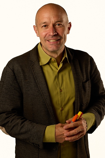 portrait von Marc Keller Inhaber make possible gmbh mit grünem hemd, anthrazit-vestion und glatze, farbigen filzstiften in den verschränkten Händen